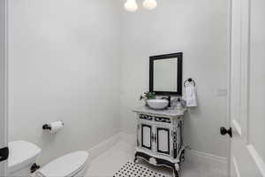 Bathroom featuring toilet, vanity, tile patterned flooring, and baseboards