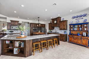 Kitchen featuring open shelves, stainless steel appliances, a spacious island, a sink, and tasteful backsplash
