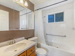 Bathroom with toilet, shower / tub combo with curtain, and vanity