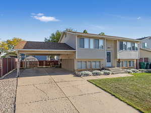 Raised ranch with driveway, a carport, and brick siding