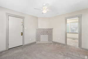 Unfurnished living room featuring ceiling fan, a fireplace with flush hearth, baseboards, and carpet