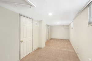 Basement with baseboards, visible vents, and light carpet