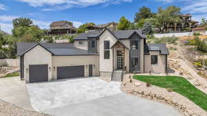 View of front facade featuring stone siding, a metal roof, a standing seam roof, and a garage