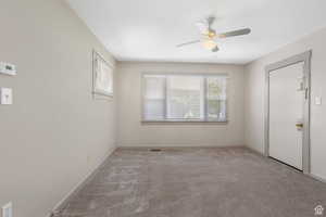 Carpeted empty room with baseboards and a ceiling fan