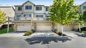 Multi unit property featuring concrete driveway, stone siding, central AC, and a garage