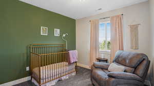 Carpeted bedroom with a crib and baseboards