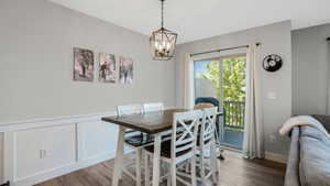 Dining space with wood finished floors, a chandelier, a wainscoted wall, and a decorative wall