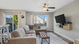 Living room with healthy amount of natural light, a ceiling fan, baseboards, and wood finished floors