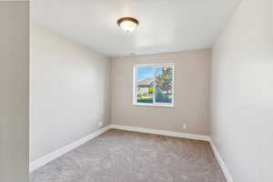 Carpeted spare room featuring baseboards