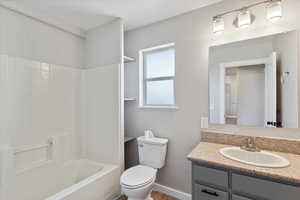 Full bathroom featuring toilet, vanity, shower / washtub combination, and baseboards