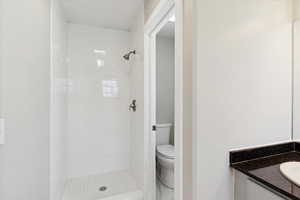 Full bathroom featuring a shower stall, toilet, and vanity