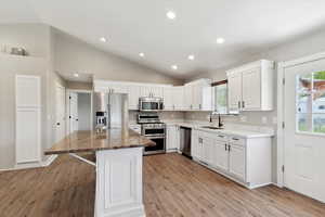 Kitchen with appliances with stainless steel finishes, lofted ceiling, a sink, light wood-style flooring, and plenty of natural light