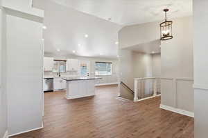 Kitchen with stainless steel dishwasher, white cabinetry, a sink, lofted ceiling, and a center island