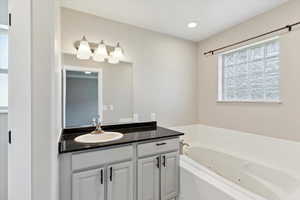 Full bath with a jetted tub and vanity