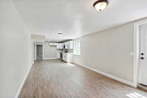 Unfurnished living room with light wood-style floors and baseboards