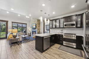 Kitchen with appliances with stainless steel finishes, open floor plan, a sink, a peninsula, and light countertops