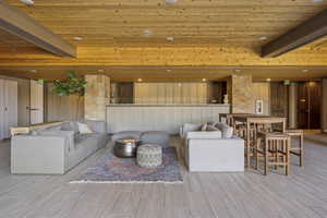 Living area with wood ceiling, wood walls, wood finish floors, and beam ceiling