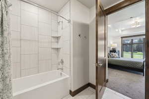 Ensuite bathroom with baseboards, shower / tub combo, tile patterned floors, and a raised ceiling