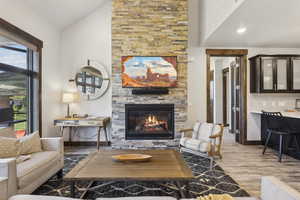 Living room featuring a fireplace, wood finished floors, baseboards, and high vaulted ceiling