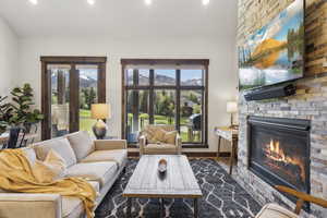 Living room with a fireplace, recessed lighting, healthy amount of natural light, dark wood-type flooring, and baseboards