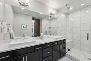 Full bathroom with a shower stall, double vanity, and recessed lighting