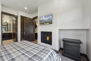 Bedroom featuring a glass covered fireplace and connected bathroom