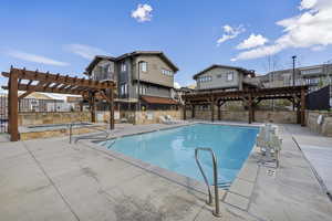 Community pool with a pergola, a patio, and fence