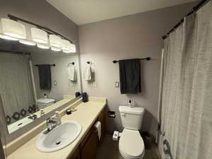 Full bath with toilet, tile patterned floors, vanity, and baseboards