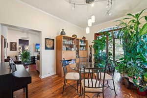 Dining space with wood-type flooring, crown molding, baseboards, and track lighting