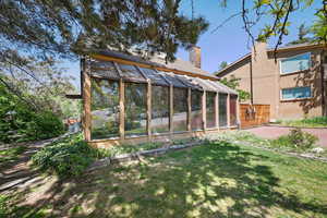 View of green lawn with a greenhouse and an outdoor structure