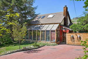 View of front facade featuring a shingled roof, a chimney, an exterior structure, and a front yard