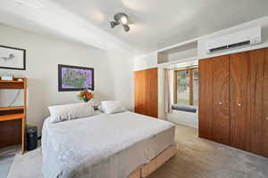 Bedroom featuring a wall unit AC and light carpet