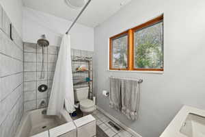 Bathroom with toilet, tile patterned flooring, a sink, and shower / bathtub combination with curtain