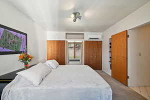 Bedroom featuring carpet floors, a wall mounted air conditioner, and two closets