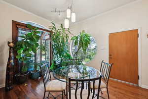 Dining room with wood-type flooring, crown molding, and baseboards