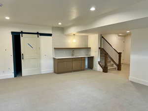 Kitchen with a barn door, light countertops, light colored carpet, recessed lighting, and open shelves