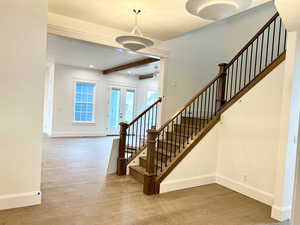 Stairs with wood finished floors, beamed ceiling, ceiling fan, and french doors