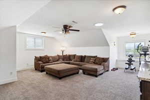 Carpeted living area featuring vaulted ceiling, plenty of natural light, baseboards, a ceiling fan, and a textured ceiling