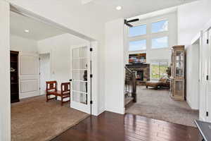 Corridor with dark wood-style floors, recessed lighting, baseboards, dark carpet, and french doors