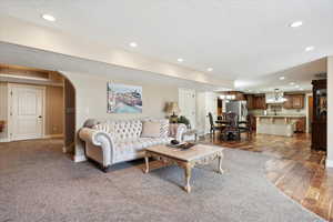Living area with recessed lighting, arched walkways, dark wood-style floors, a textured ceiling, and baseboards
