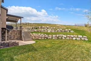 View of grassy yard with stairs and a patio area