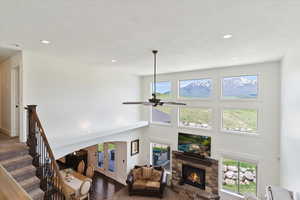 Living room with dark wood finished floors, a fireplace, ceiling fan, healthy amount of natural light, and a high ceiling