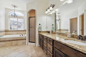 Full bathroom featuring a chandelier, a garden tub, a shower stall, double vanity, and tile patterned floors
