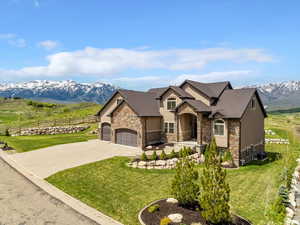 French country home with stone siding, a garage, driveway, and a mountain view