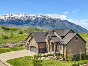 View of front facade featuring stone siding, a garage, a mountain view, and driveway