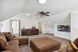 Living area featuring lofted ceiling, light carpet, a ceiling fan, baseboards, and recessed lighting