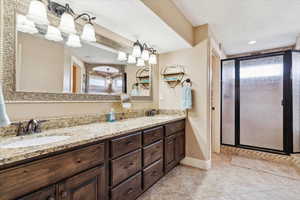 Full bathroom featuring a stall shower, double vanity, baseboards, a textured ceiling, and tile patterned floors