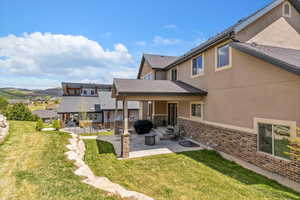 Back of property featuring a patio area, a lawn, and stucco siding