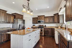 Kitchen featuring stainless steel appliances, a sink, white cabinets, dark brown cabinets, and recessed lighting