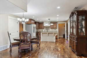Dining space with dark wood finished floors, a chandelier, recessed lighting, baseboards, and a textured ceiling